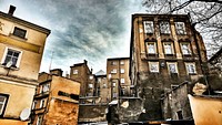 A group of old apartment buildings with fire damage and gray clouds in the background.. Original public domain image from Wikimedia Commons