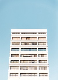 A white residential building against a pale blue sky. Original public domain image from Wikimedia Commons
