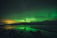Colorful orange and green Northern Lights being reflected on the water surface in Th&oacute;rsm&ouml;rk, Iceland. Original public domain image from <a href="https://commons.wikimedia.org/wiki/File:Reflecting_the_sky_(Unsplash).jpg" target="_blank">Wikimedia Commons</a>