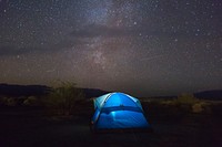 Blue tents glows in against a dark starry night sky. Original public domain image from Wikimedia Commons