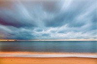 A scenic sunset with cloudy skies casting over Playa de la Misericordia in Malaga. Original public domain image from Wikimedia Commons