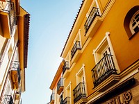 An alley with two elegant yellow buildings on its two sides in Málaga. Original public domain image from Wikimedia Commons