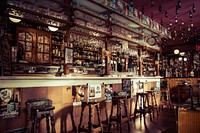 Bar with stools, glass cups and empty bottles attached to the roof in Madrid. Original public domain image from <a href="https://commons.wikimedia.org/wiki/File:Cerveceria_La_Mayor_(Unsplash).jpg" target="_blank">Wikimedia Commons</a>