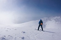 A man walking in skis on a slight slope near medium-sized mountains. Original public domain image from <a href="https://commons.wikimedia.org/wiki/File:Blown_(Unsplash).jpg" target="_blank" rel="noopener noreferrer nofollow">Wikimedia Commons</a>