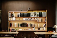 An elegant bookcase at the back of a room with several tables. Original public domain image from Wikimedia Commons