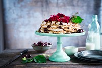 A cake stand with a cream cake covered in red flowers and cherries on a wooden table. Original public domain image from <a href="https://commons.wikimedia.org/wiki/File:The_Ugliest_Cake_in_the_World_(Unsplash).jpg" target="_blank" rel="noopener noreferrer nofollow">Wikimedia Commons</a>