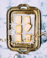 An overhead shot of cookies and paper snowflakes on a golden tray. Original public domain image from Wikimedia Commons
