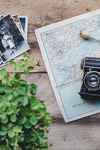 A macro shot of a wooden desk table with a map, camera, plants and other items. Original public domain image from Wikimedia Commons