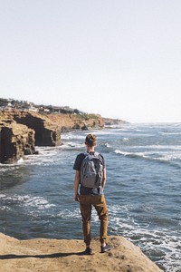 Man in pants with backpack stands by Sunset Cliffs. Original public domain image from Wikimedia Commons