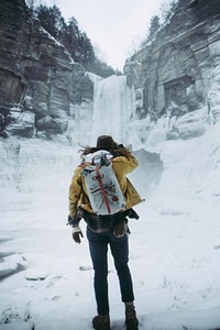 A hiker staring at a winter waterfall from the bottom of a mountain in Ithaca, New York. Original public domain image from <a href="https://commons.wikimedia.org/wiki/File:Falls_(Unsplash).jpg" target="_blank" rel="noopener noreferrer nofollow">Wikimedia Commons</a>