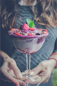 A woman holding purple Chia Pudding covered with berries and mint leaves in a glass cup in the Lima Region. Original public domain image from <a href="https://commons.wikimedia.org/wiki/File:Lima_Region_chia_pudding_(Unsplash).jpg" target="_blank" rel="noopener noreferrer nofollow">Wikimedia Commons</a>