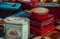 Old stuff packaged in tin and boxes stacked together in a flea market at lewis cubits square.. Original public domain image from Wikimedia Commons