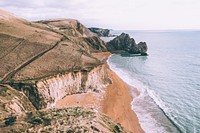 Drone view of the coastal cliffs above sand beach at Durdle Door. Original public domain image from Wikimedia Commons