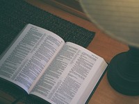 An open Bible next to a table lamp.. Original public domain image from Wikimedia Commons