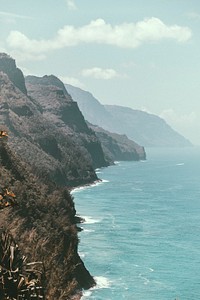 The side of a rocky cliff along a bright blue ocean in Kauai. Original public domain image from Wikimedia Commons