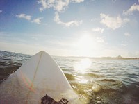 The front of a surfboard in the water facing the sun in Peniche. Original public domain image from Wikimedia Commons