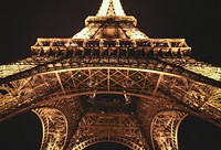 A centered shot looking up at the Eiffel Tower in Paris illuminated at night. Original public domain image from Wikimedia Commons