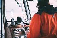 A captain steering the boat as he looks out the into the water.. Original public domain image from Wikimedia Commons