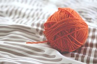 An orange wool ball of yarn on a blanket. Original public domain image from Wikimedia Commons