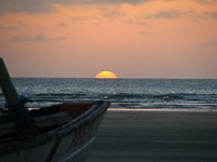 The golden sun resting on the horizon at sea with a fishing boat in the foreground. Original public domain image from Wikimedia Commons