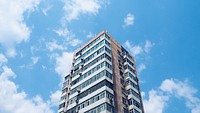 Looking up at a city apartment highrise against a blue sky. Original public domain image from Wikimedia Commons