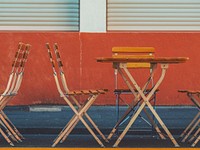 Empty wooden table and chairs against a dark red wall in Cologne. Original public domain image from Wikimedia Commons