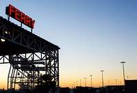 Neon "ferry" sign glows over an industrial structure at sunset. Original public domain image from Wikimedia Commons