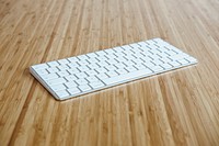 A white wireless Apple keyboard on a wooden surface. Original public domain image from Wikimedia Commons