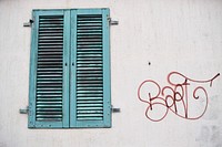 Red graffiti tag on white wall next to worn green window shutter. Original public domain image from <a href="https://commons.wikimedia.org/wiki/File:Graffiti_and_window_shutter_(Unsplash).jpg" target="_blank" rel="noopener noreferrer nofollow">Wikimedia Commons</a>