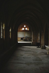 Dimly lit hallway with a bike at the end. Stone Archway shows off historic architecture. Original public domain image from Wikimedia Commons