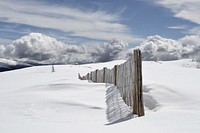 The end of a wooden fence traveling along a snow covered mountain. Original public domain image from Wikimedia Commons