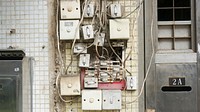 Multiple apartment buzzer switches with exposed wires on a wall.. Original public domain image from Wikimedia Commons