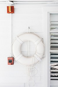 A white life belt on a white wooden wall next to a window. Original public domain image from Wikimedia Commons