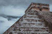 Looking up at an ancient stone pyramid under a cloudy sky in Chichén Itzá. Original public domain image from Wikimedia Commons