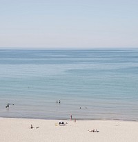 View of the swimmers on the sandy beach of the calm ocean. Original public domain image from Wikimedia Commons