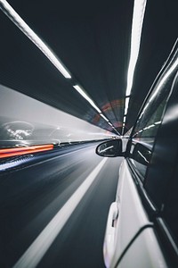 Long exposure photo of a white car driving through a tunnel with traffic lights. Original public domain image from Wikimedia Commons