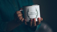 A woman with pink fingernails holding a mug that says head gardener in green writing in New Delhi. Original public domain image from Wikimedia Commons