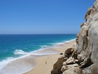 Rock cliff overlooking a person standing on the sand beach coastline at Mexico. Original public domain image from Wikimedia Commons