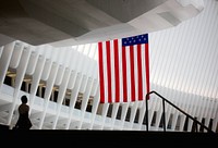 An American flag hands off a balcony inside a modern building. Original public domain image from Wikimedia Commons