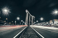 Starbursts of light shine on a city street with unique architecture in Singapore. Original public domain image from Wikimedia Commons