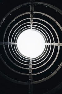 Black and white shot of circular spiral circular architecture from below with sky light. Original public domain image from <a href="https://commons.wikimedia.org/wiki/File:Spiral_architecture_and_light_(Unsplash).jpg" target="_blank" rel="noopener noreferrer nofollow">Wikimedia Commons</a>
