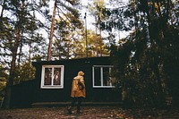 Person standing in front of a cabin. Original public domain image from Wikimedia Commons
