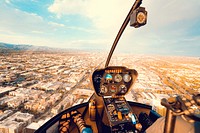 Inside the cockpit of a helicopter flying above a busy city downtown. Original public domain image from Wikimedia Commons