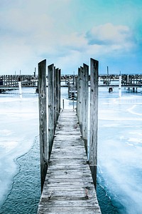 A narrow wooden footbridge extends across a frozen lake. Original public domain image from Wikimedia Commons