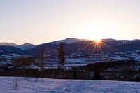 Setting sun diving behind a snow-covered mountain ridge in Silverthorne. Original public domain image from <a href="https://commons.wikimedia.org/wiki/File:Sunset_over_mountains_in_Silverthorne_(Unsplash).jpg" target="_blank" rel="noopener noreferrer nofollow">Wikimedia Commons</a>