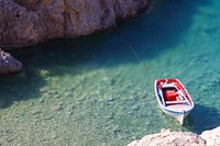 White and red boat toy docked on brown rock. Original public domain image from Wikimedia Commons