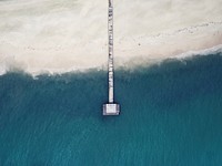 Drone aerial view of a long wooden pier at the sand beach in Hon'daafushi. Original public domain image from Wikimedia Commons