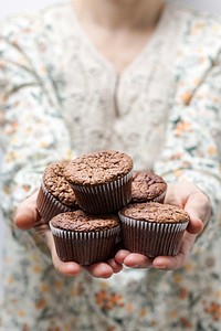 A woman holding several cupcakes in her hands. Original public domain image from <a href="https://commons.wikimedia.org/wiki/File:Home_made_muffins_(Unsplash).jpg" target="_blank" rel="noopener noreferrer nofollow">Wikimedia Commons</a>