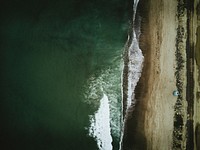 Drone aerial view of the ocean washing on a sand beach at San Clemente. Original public domain image from <a href="https://commons.wikimedia.org/wiki/File:Cloudy_Over_Seas_(Unsplash).jpg" target="_blank" rel="noopener noreferrer nofollow">Wikimedia Commons</a>
