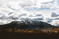 Yellow undulating hills at the foot of a snowy mountain ridge in Telluride. Original public domain image from <a href="https://commons.wikimedia.org/wiki/File:Snowy_mountain_massif_in_Telluride_(Unsplash).jpg" target="_blank" rel="noopener noreferrer nofollow">Wikimedia Commons</a>
